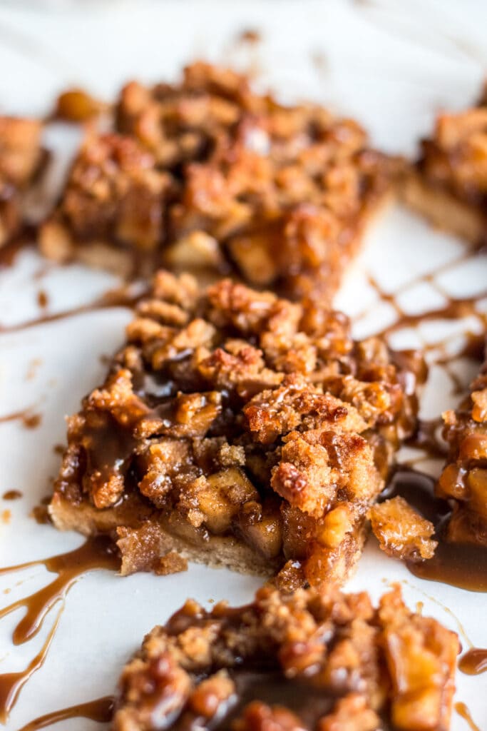 A close up image of a healthy apple crumbl bar drizzled with paleo caramel sauce