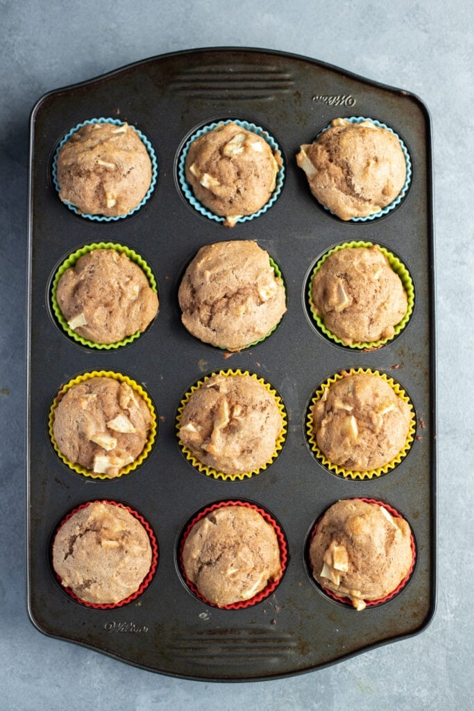 Apple muffins recipe in a dark muffin tin on a grey background