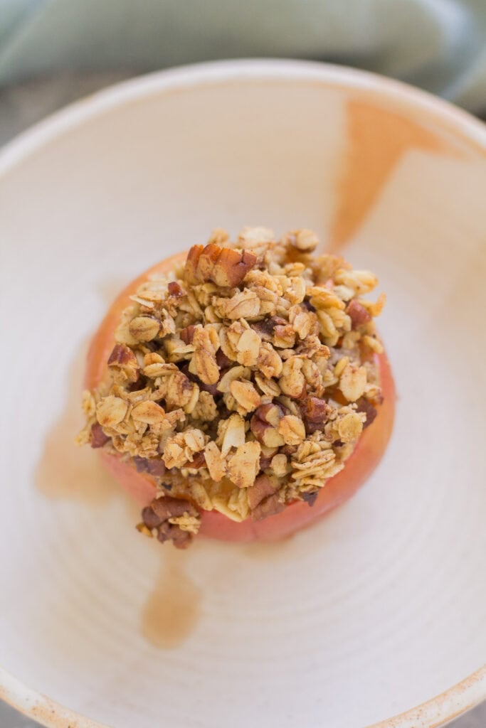 a top down view of a whole healthy baked apple in a white bowl