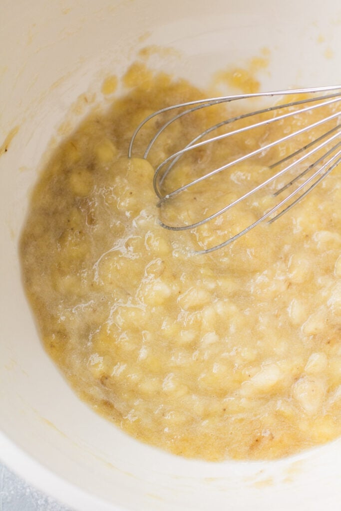 Wet ingredients for banana muffins being mixed together in a white bowl