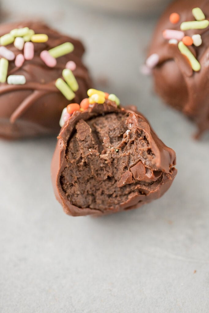 A close up of a gluten free brownie truffle with a bite taken out of it.