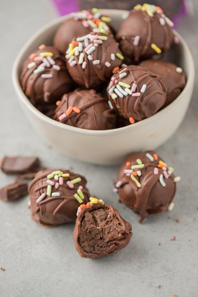 Brownie Truffles in a bowl on a grey background with a few scattered off to the side.