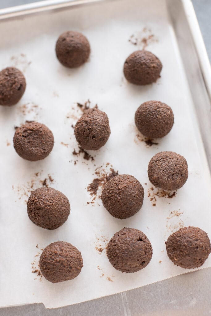 Healthy brownie truffles rolled out on a parchment lined baking sheet heading into the freezer
