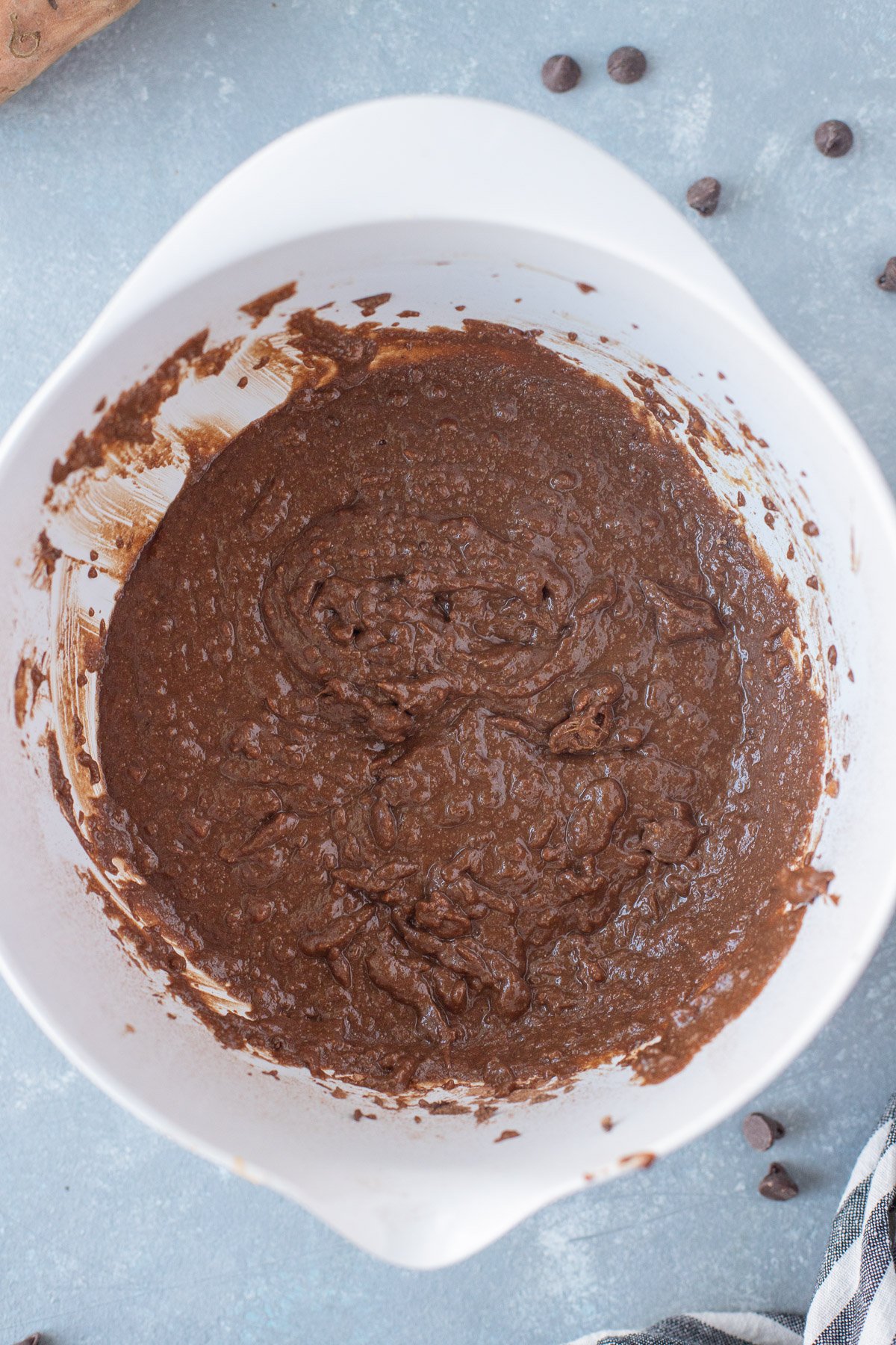 Sweet potato brownie batter in a white mixing bowl on a grey background