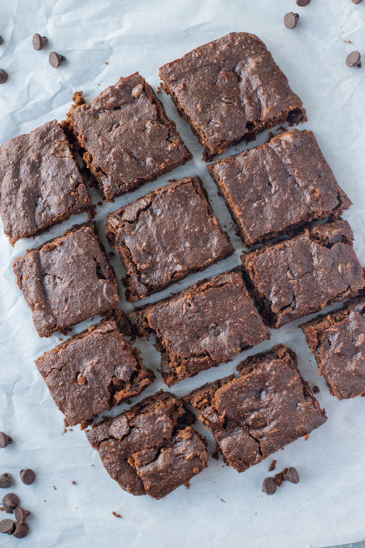 Freshly cut sweet potato brownies on a grey background with chocolate chips on the side