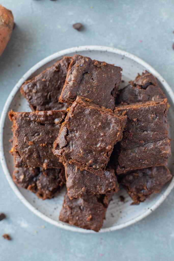A white plate piled with sweet potato brownies on a grey background