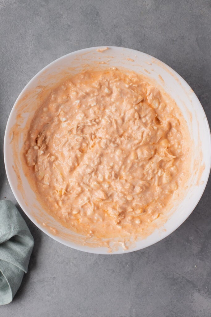 healthy buffalo chicken dip mixed together in a white bowl before going in the oven