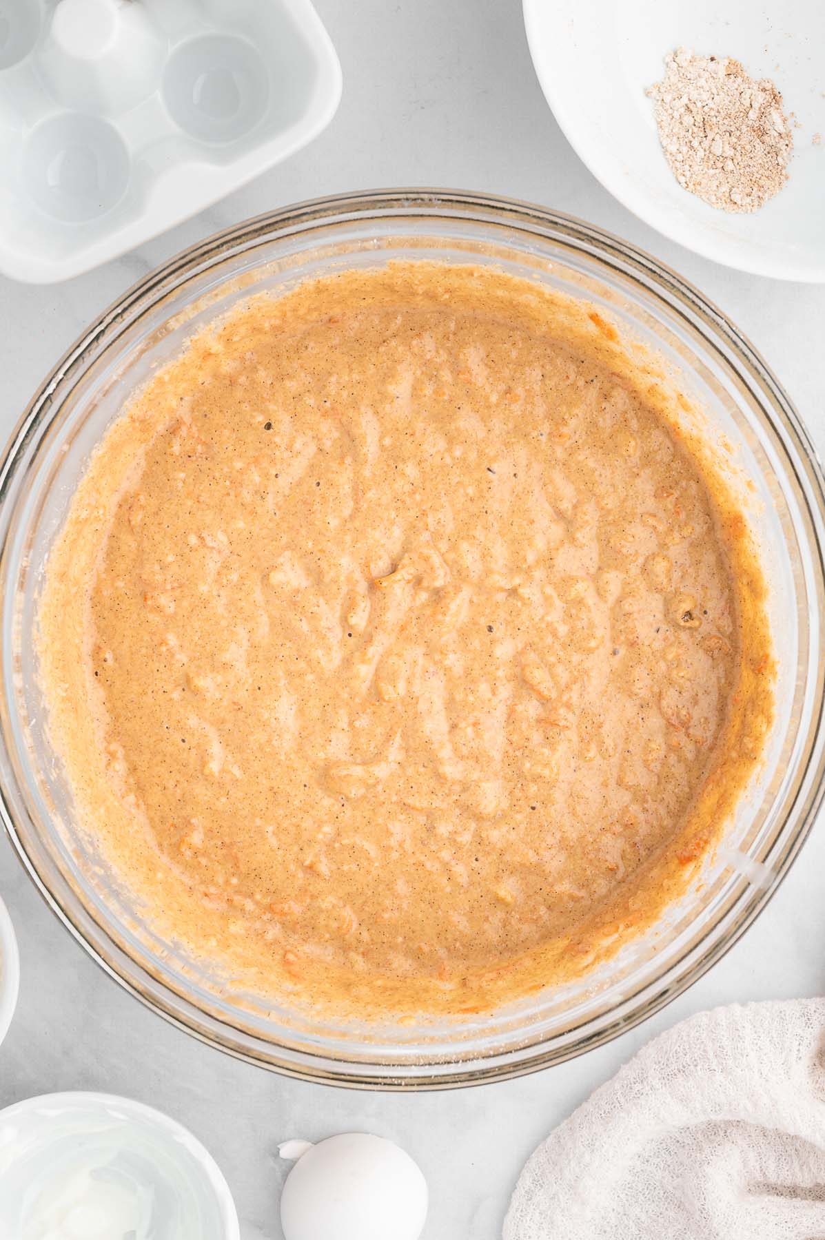 Batter for healthy carrot cake in a clear bowl on a marble background