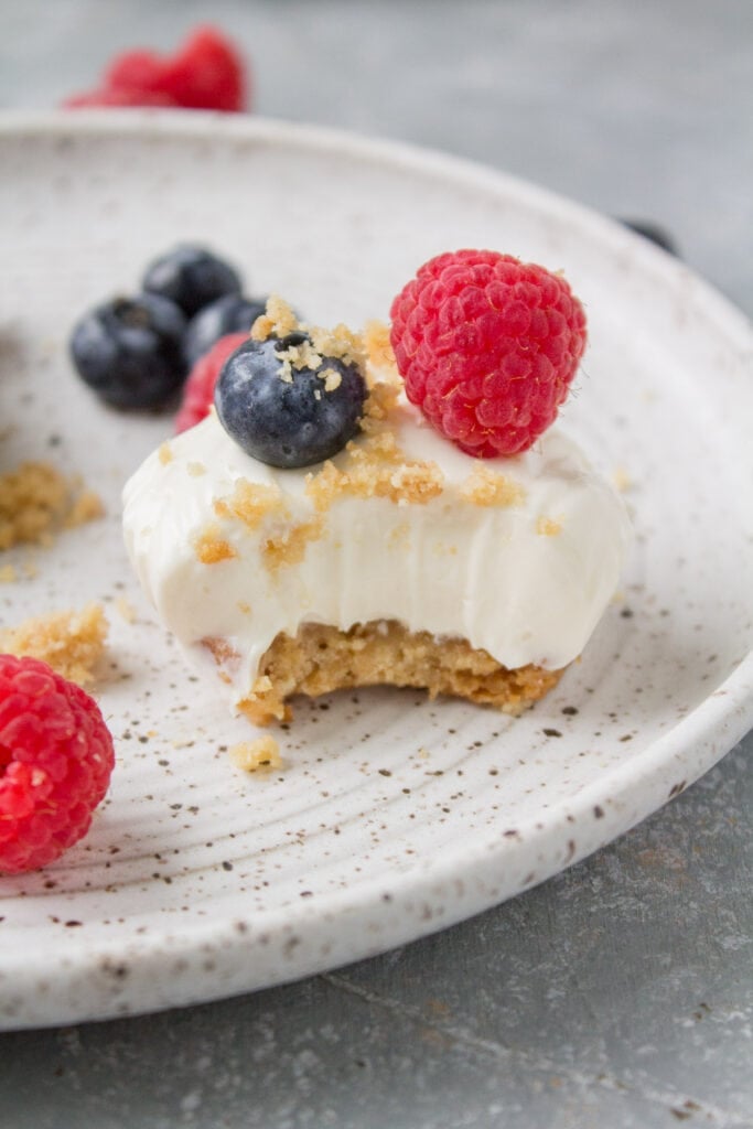 A close up image of a mini greek yogurt cheesecake with a bite taken out of it.