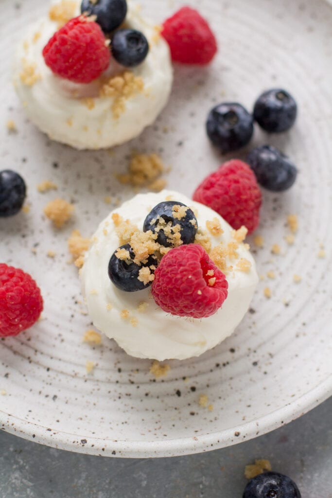A close up image of mini low fat healthy cheesecakes on a white speckled plate.
