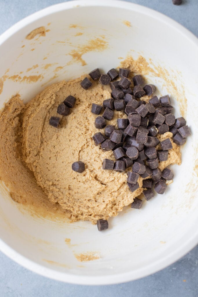 A collage showing step by step how to make whole wheat chocolate chip cookies - mixing together the batter and adding in the chocolate