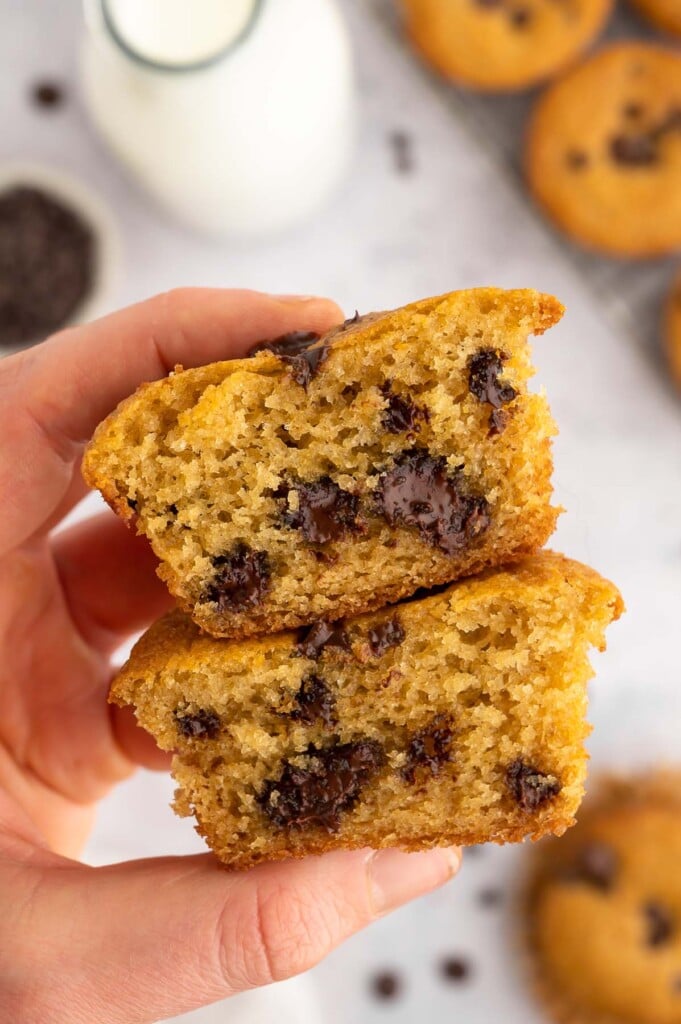 Two halves of a healthy chocolate chip muffin stacked on each other held up by a hand. 