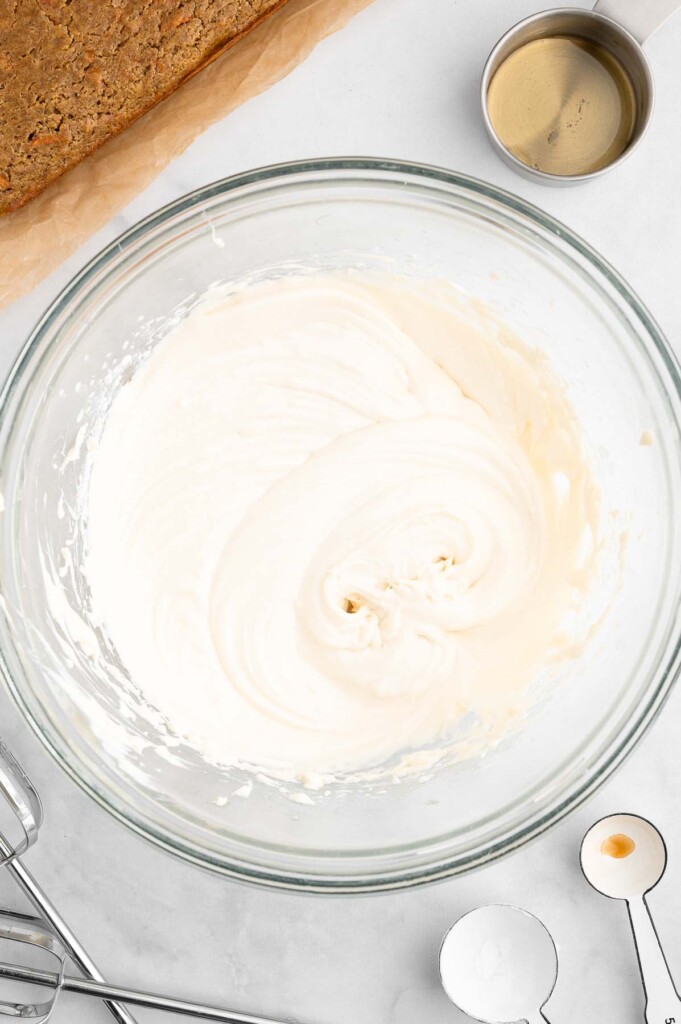 A clear bowl of healthy cream cheese frosting on a white background