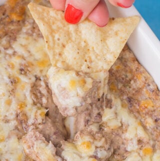 A chip scooping up a bite of healthy bean dip from a dish