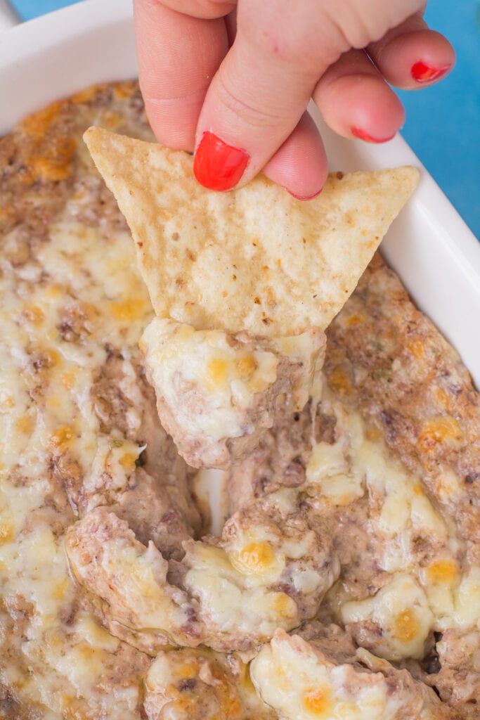 A chip scooping up a bite of healthy bean dip from a dish