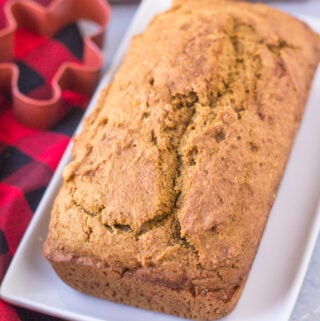 Healthy Gingerbread Loaf on a white rectangle dish with a red checked linen and a cookie cutter off to the side