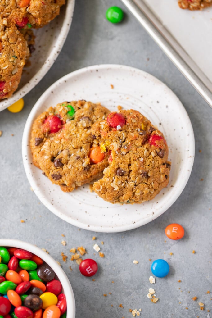 An overhead shot of two healthy monster cookies on a white plate with m&ms on the side