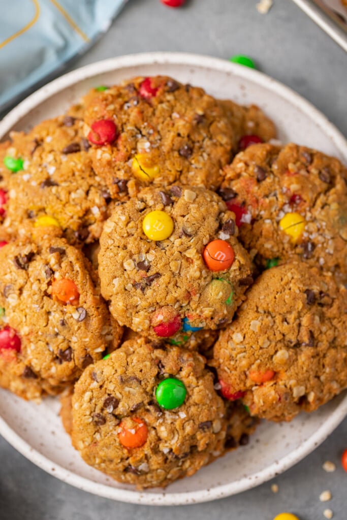 An overhead shot of a white plate with healthy monster cookies on it