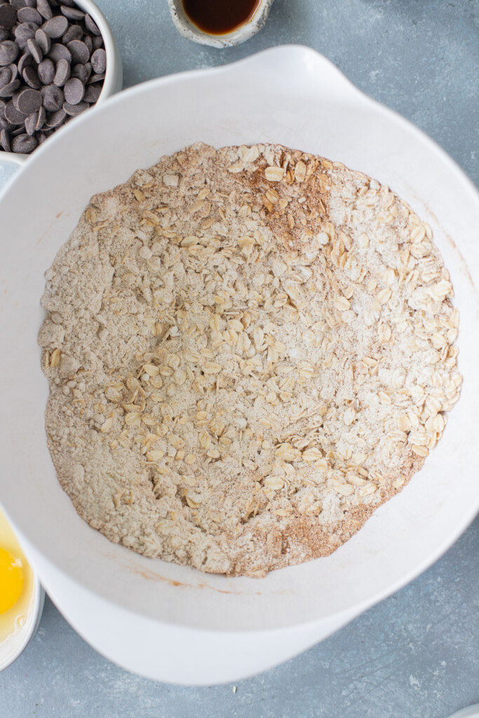 Dry ingredients in a white bowl to make healthy oatmeal chocolate chip cookies.