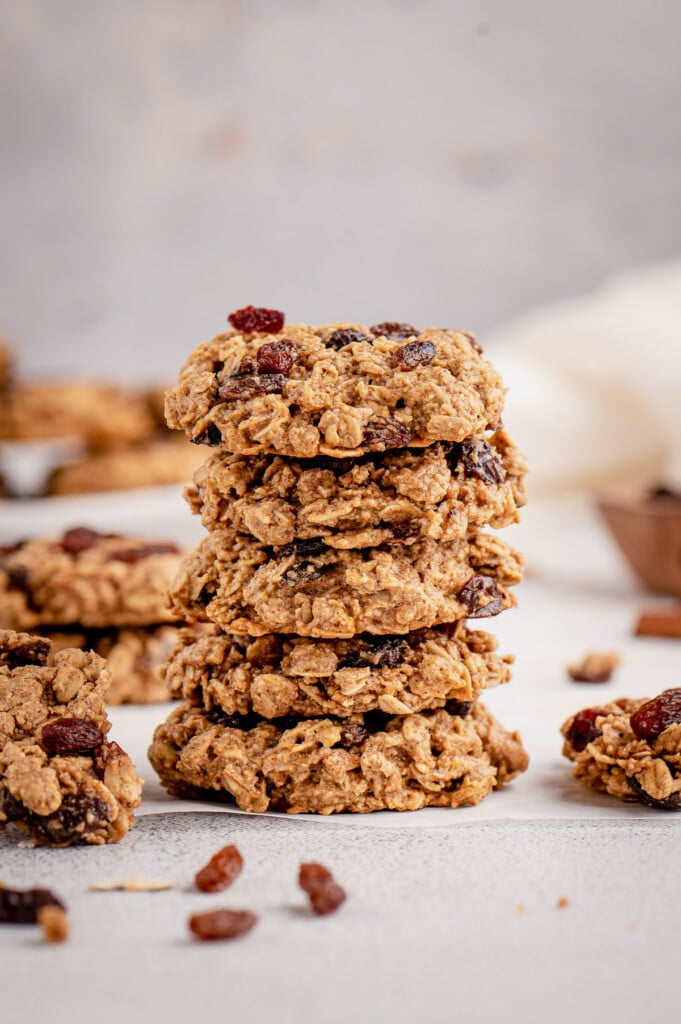 A stack of healthy oatmeal raisin cookies on a gray background with cookies around it