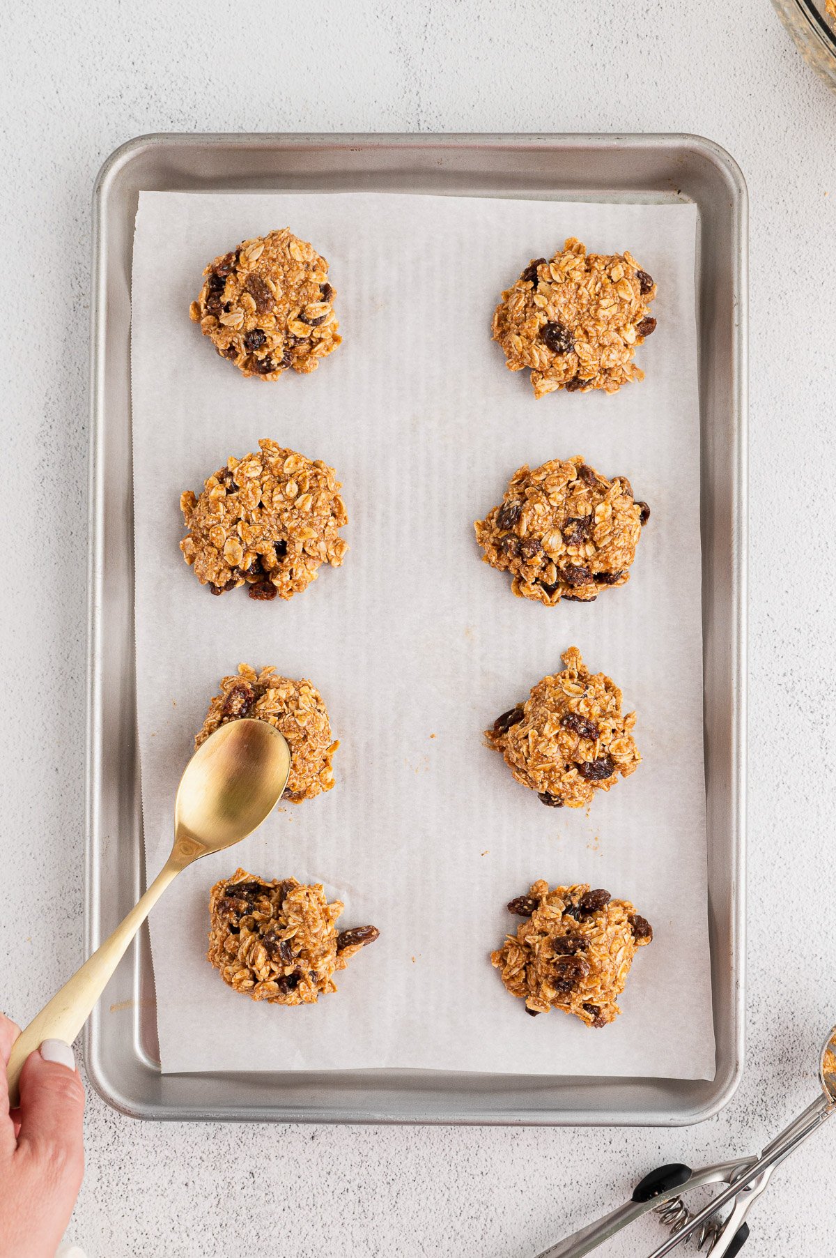 Healthy Oatmeal Raisin Cookie dough being scooped onto a lined baking sheet