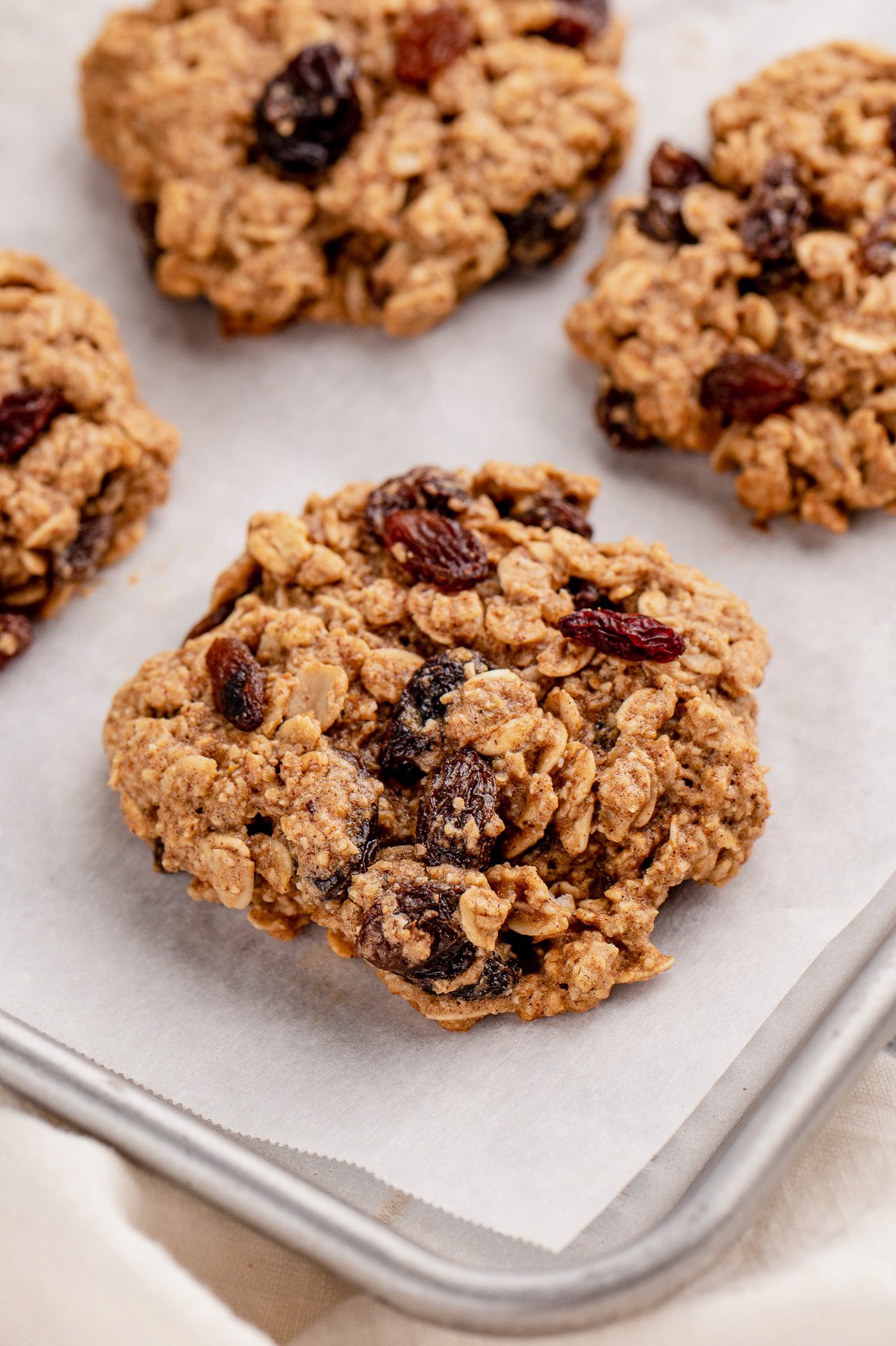 A close up of an oatmeal raisin cookie on a lined baking sheet 