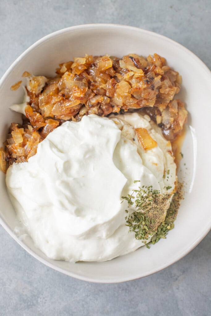 A bowl with ingredients for healthy onion dip before being mixed