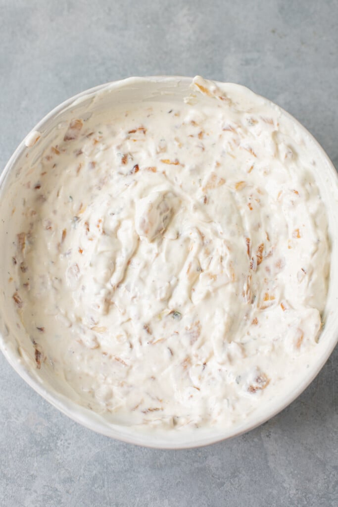 A bowl of healthy onion dip after being mixed on a grey background