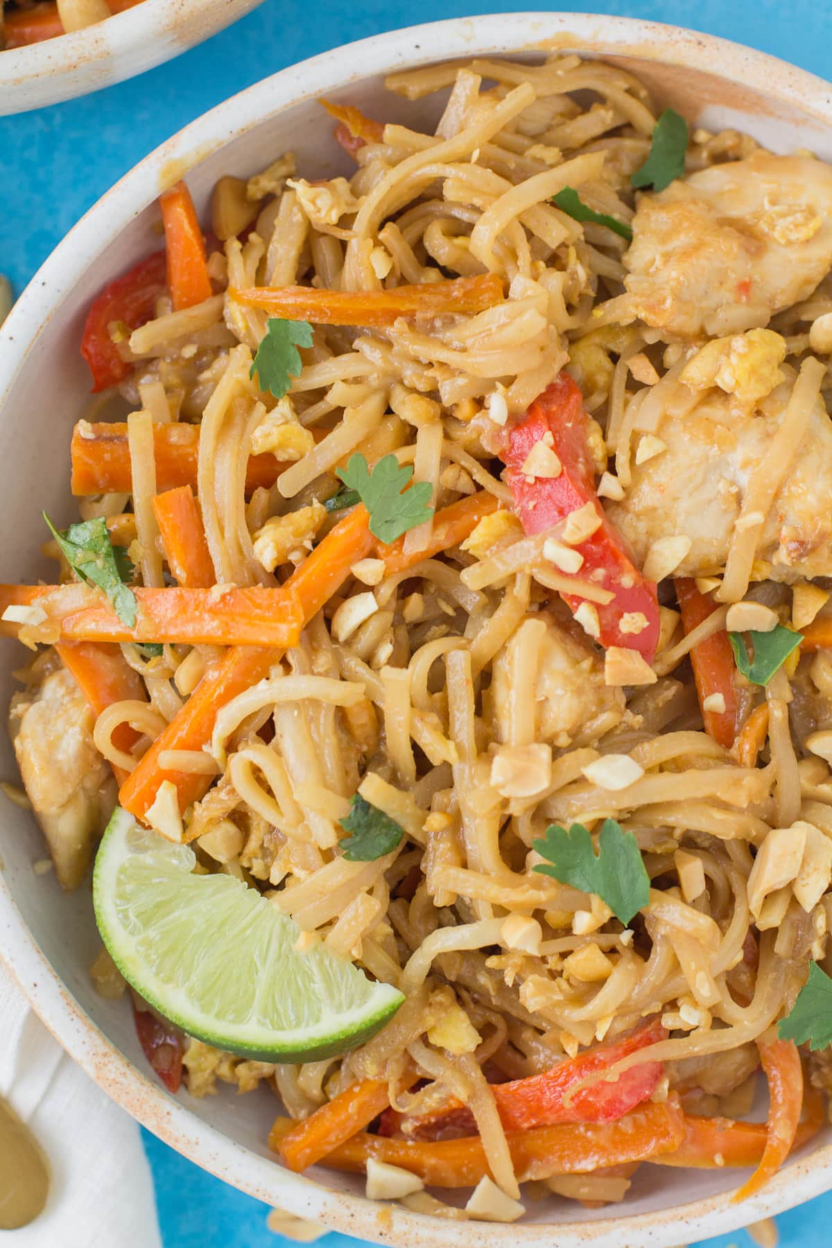 a bowl of Healthy Chicken Pad Thai on a bright blue background