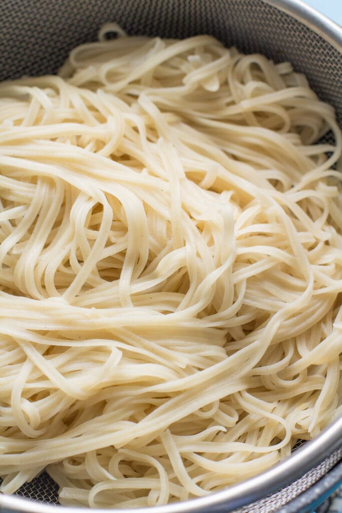 Noodles for pad thai being boiled in a pot