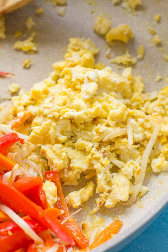 eggs being scrambled for pad thai in a white pan