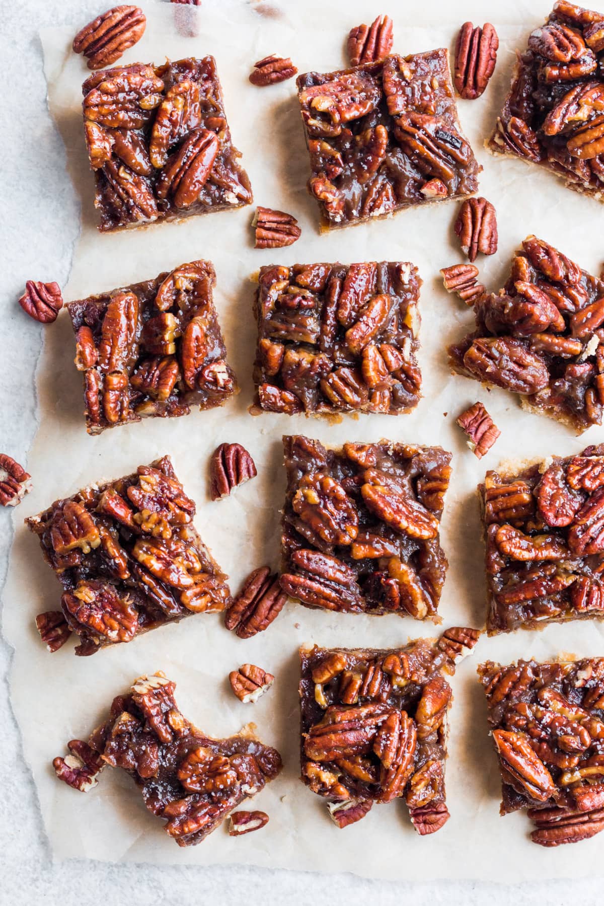 An overhead shot of Healthy Pecan Pie Bars cut on parchment paper