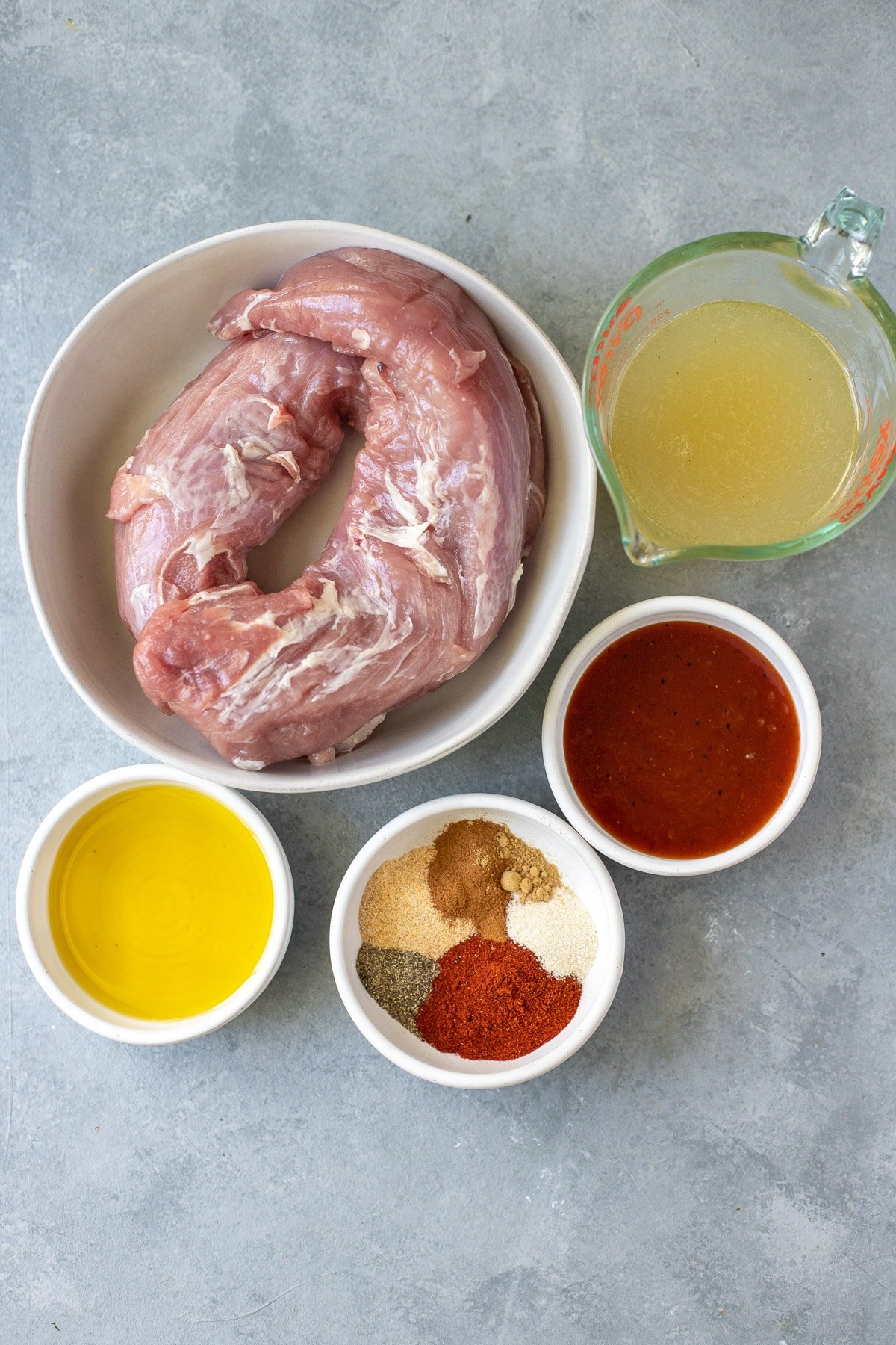 Ingredients for healthy pulled pork in small white bowls on a grey background