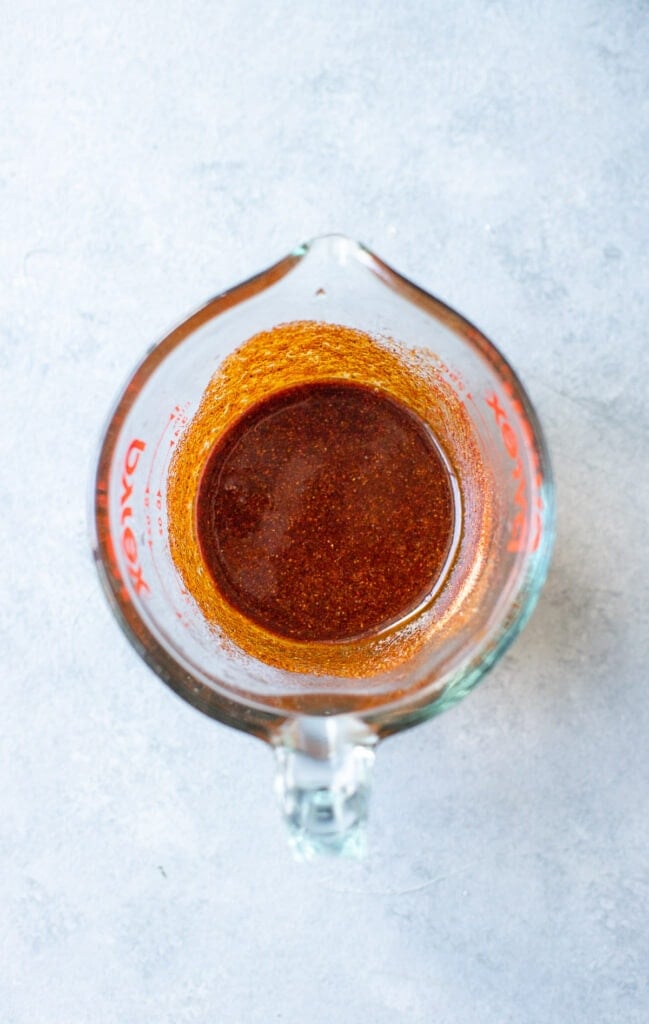 Marinade for healthy slow cooker pulled pork mixed together in a measuring cup on a grey background