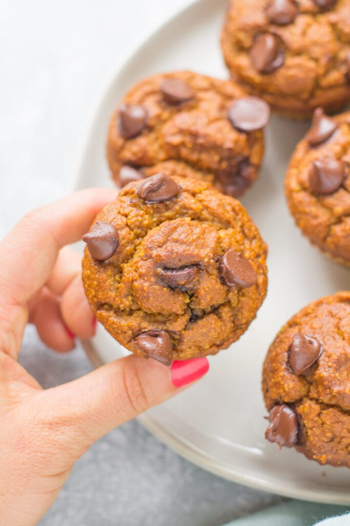 Healthy Pumpkin Muffins on a plate with a hand holding up a muffin