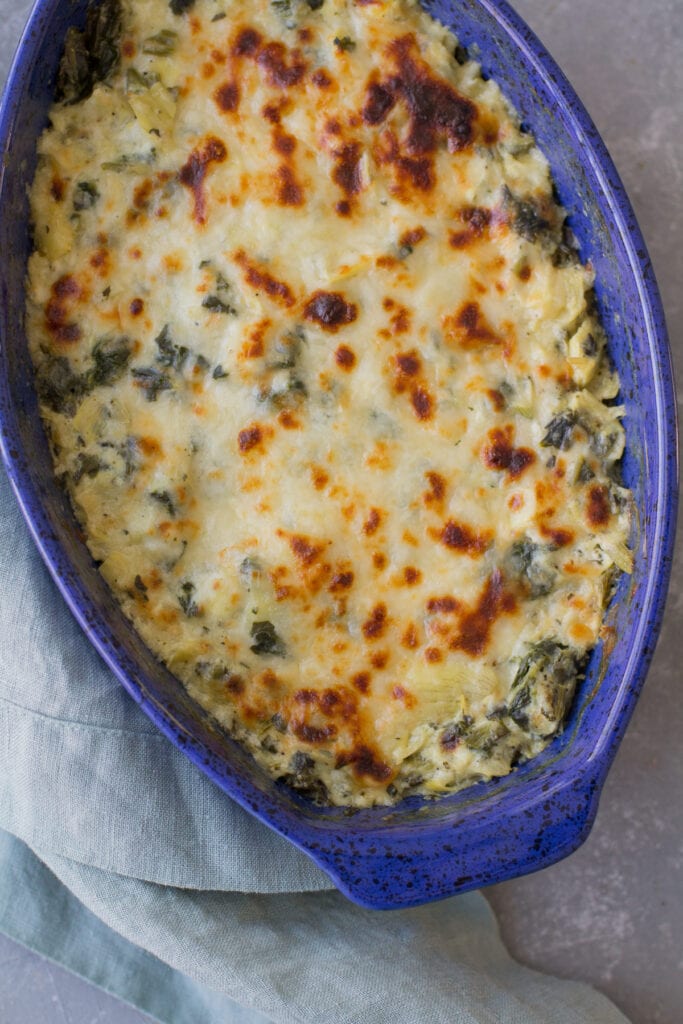 healthy spinach artichoke dip fresh out of the oven. the cheese is browned on top and super melty.