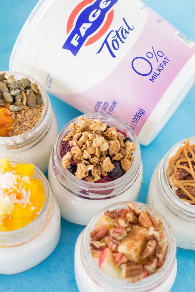 5 Healthy Yogurt Parfaits in glass jars with a carton ofFAGE Yogurt off to the side