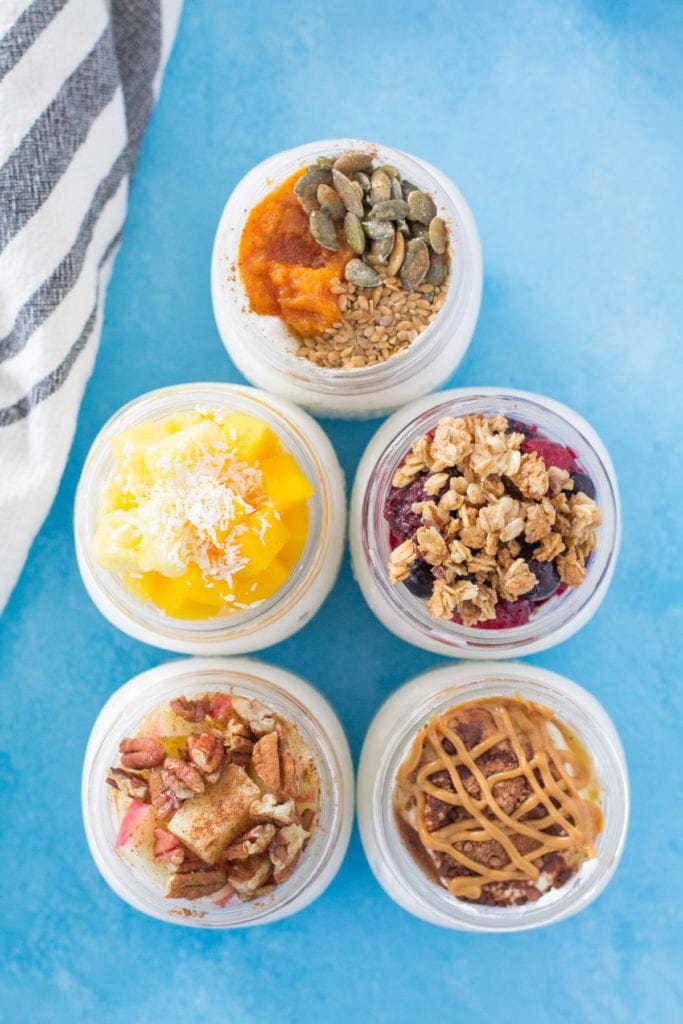 5 Healthy Yogurt Parfaits with their toppings on a blue background.