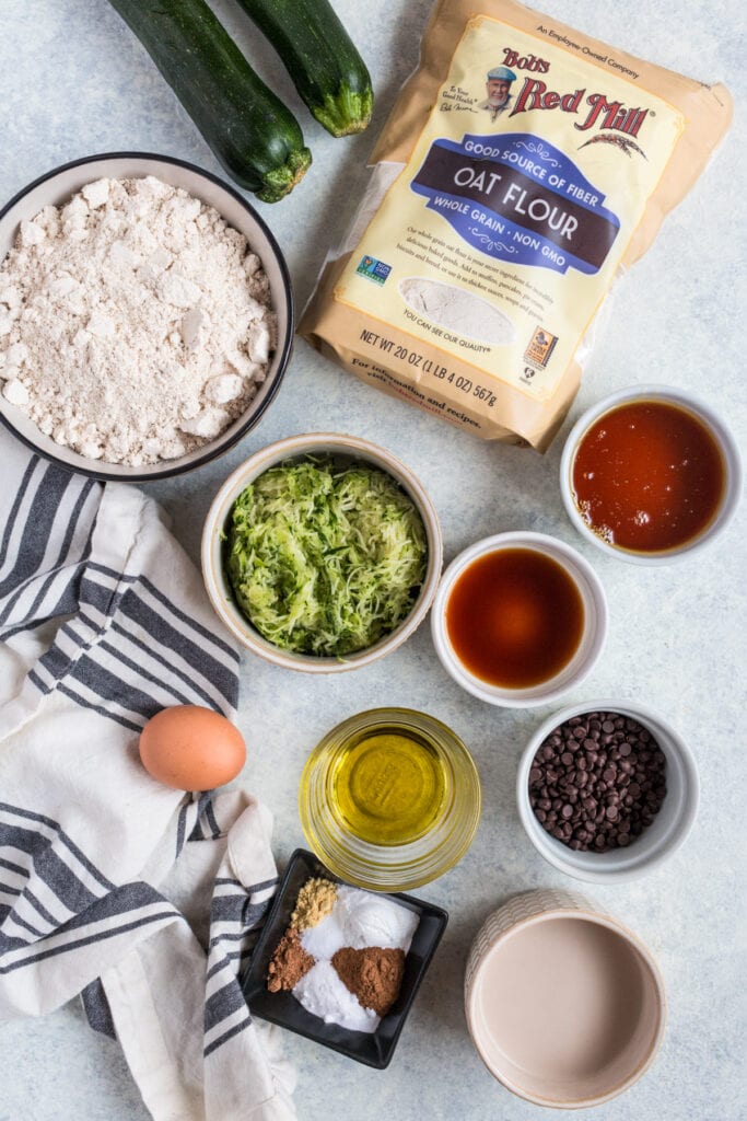 Ingredients for Healthy Zucchini Bread in small white bowls on a grey background