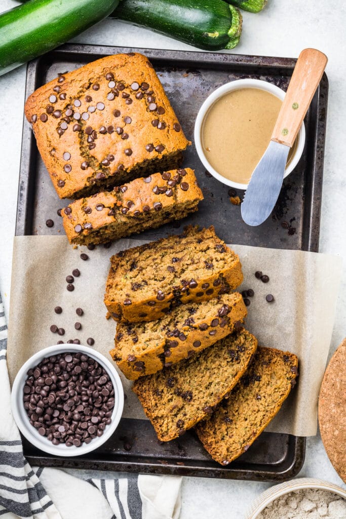 easy healthy Zucchini bread sliced on a tray with chocolate and zucchini off to the side
