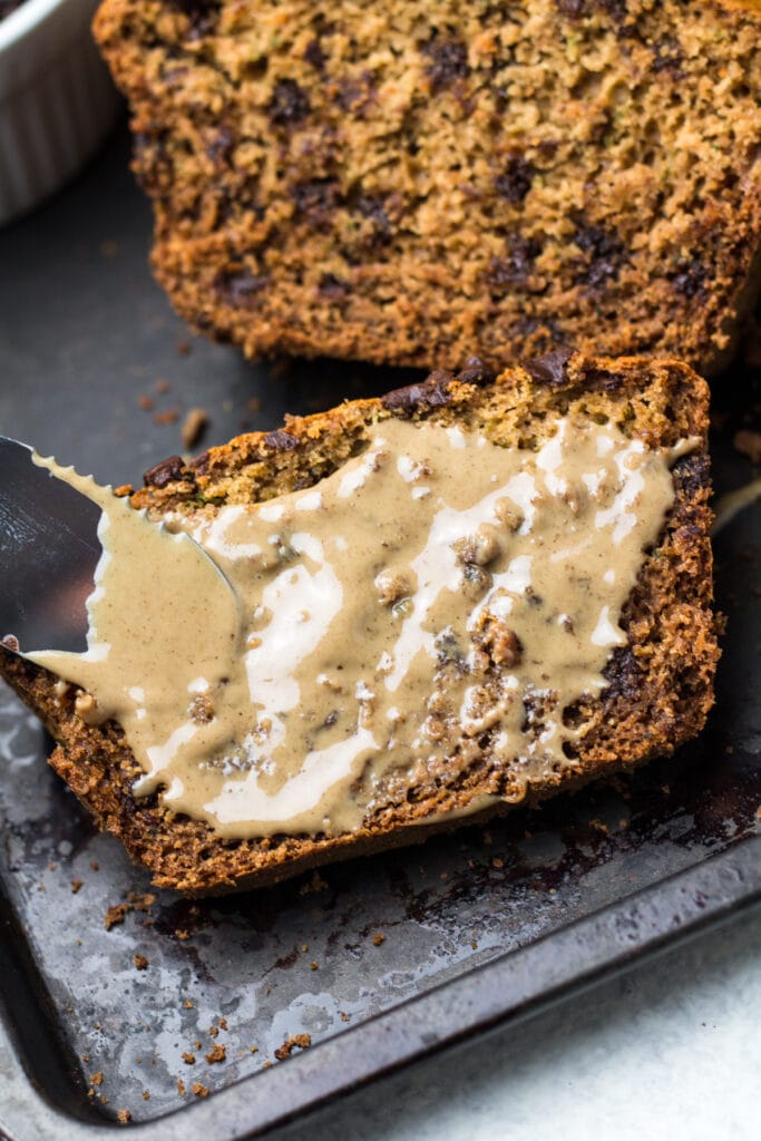A slice of healthy zucchini bread with nut butter on top of it