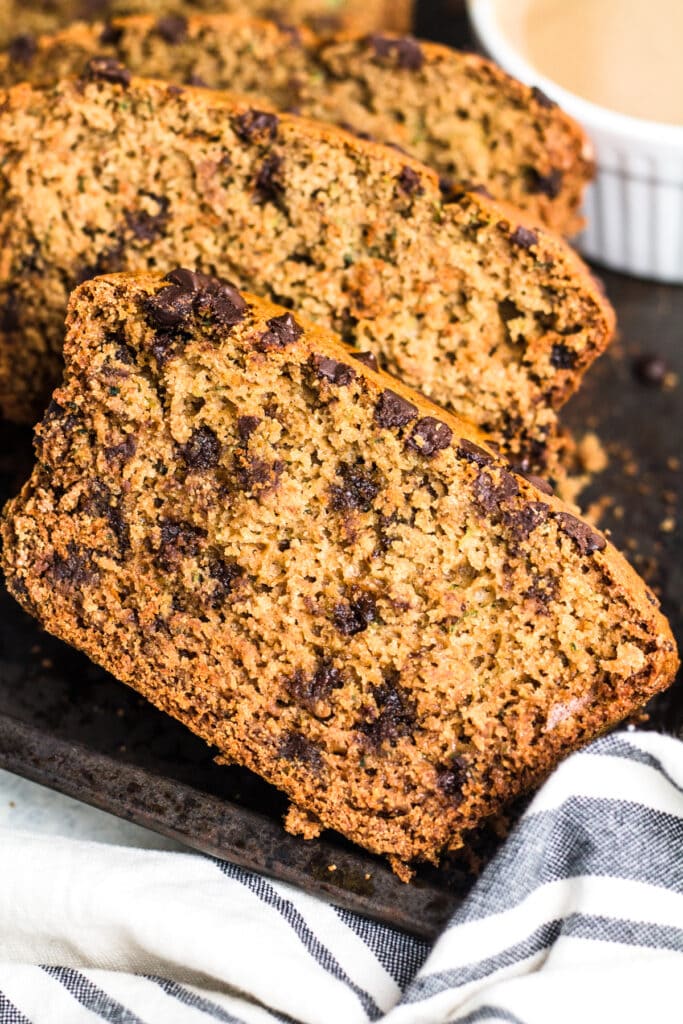 A close up image of a slice of dairy free zucchini bread on a grey tray