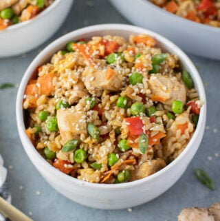 An overhead bowl of Healthy Fried Rice on a grey background with fried rice in the background