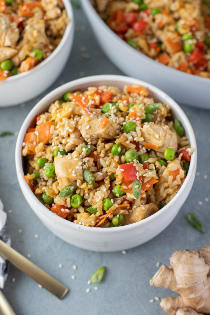 An overhead bowl of Healthy Fried Rice on a grey background with fried rice in the background
