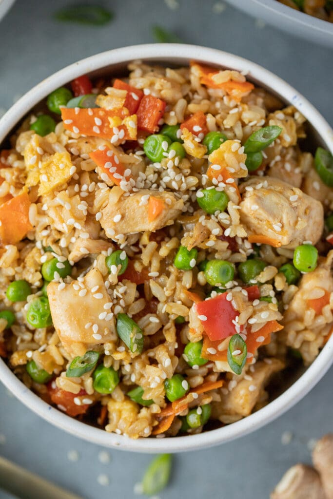 A close up of a bowl of homemade fried rice on a grey background