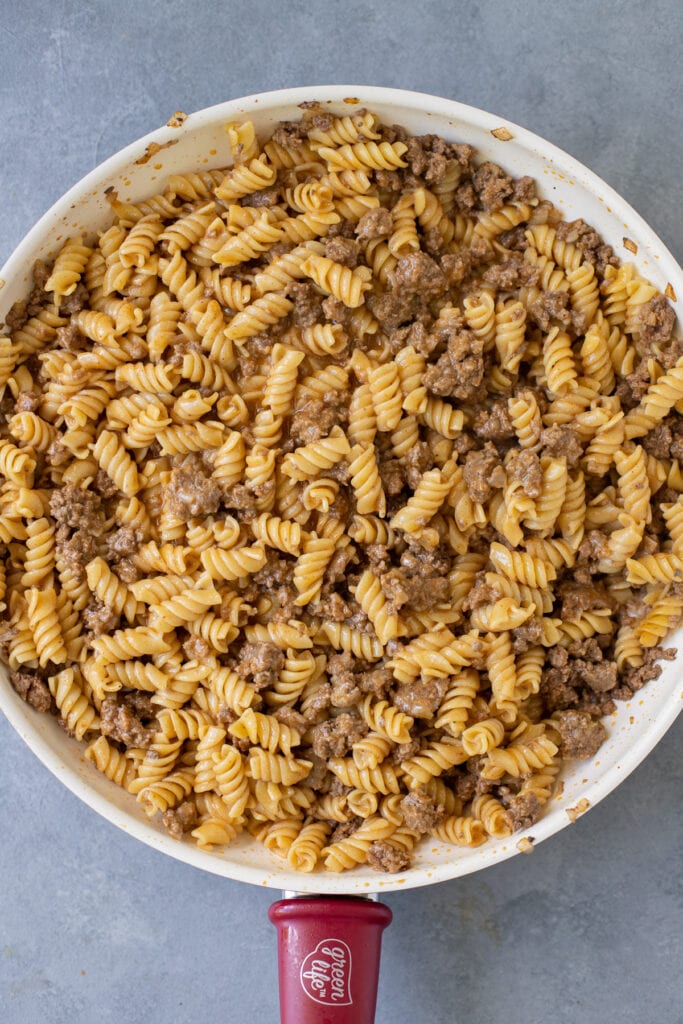 An overhead shot of homemade hamburger helper in a white pan on a grey background