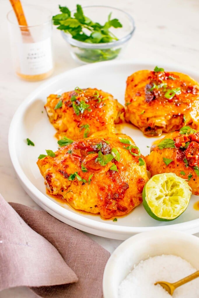 Honey Chipotle Chicken thighs and a halved lime on a white plate