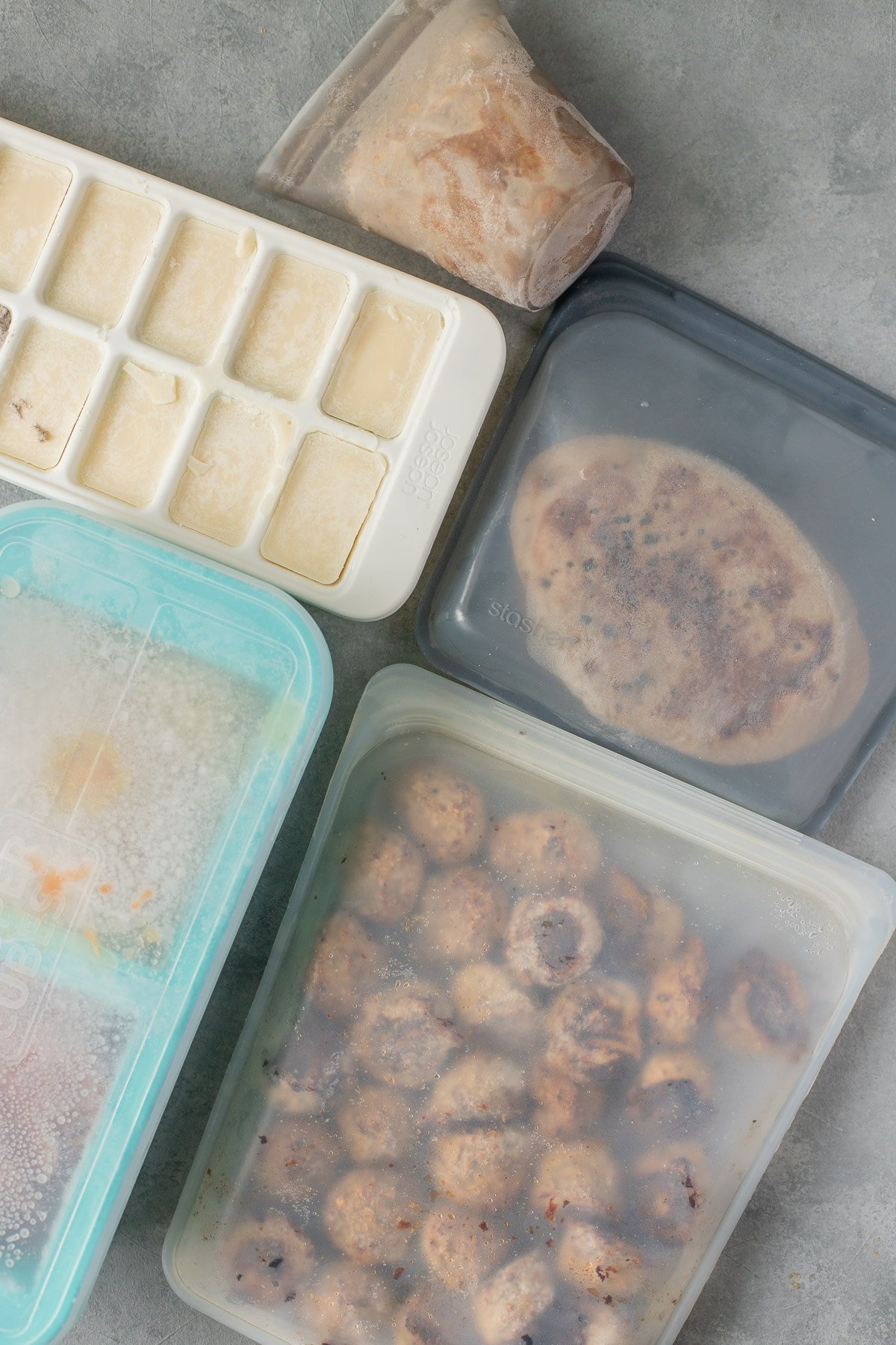 Frozen foods in containers on a grey background