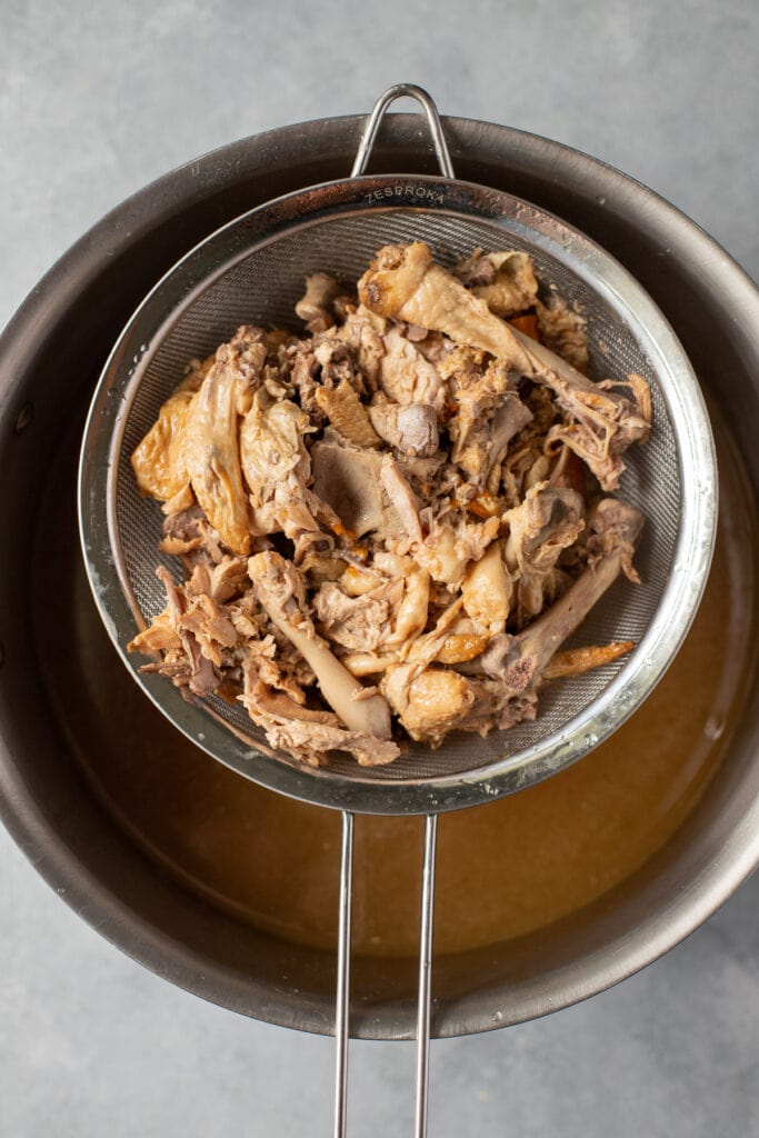 a close up of bone broth being strained in a pot