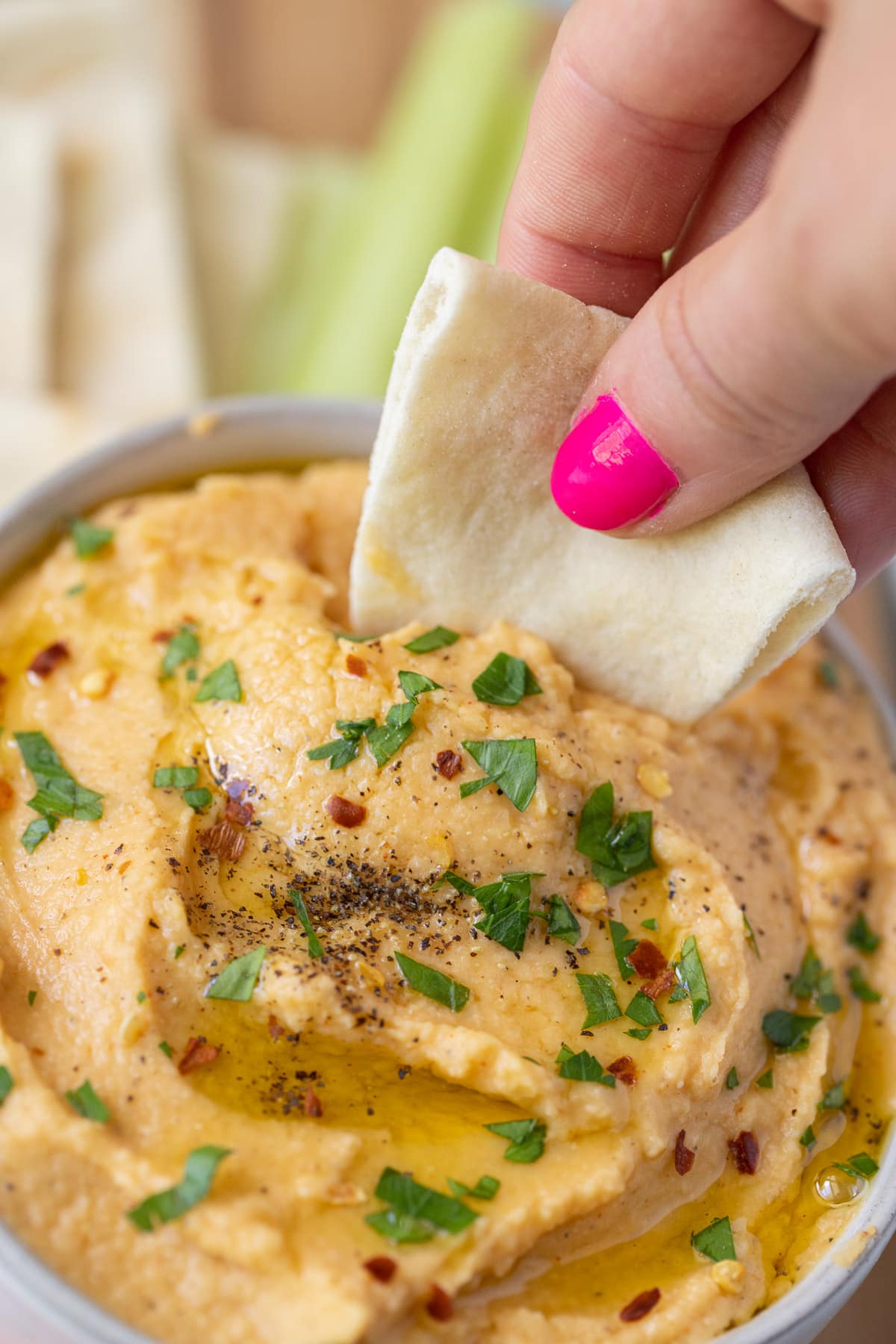 The best authentic hummus recipe with a piece of pita taking a scoop out of it